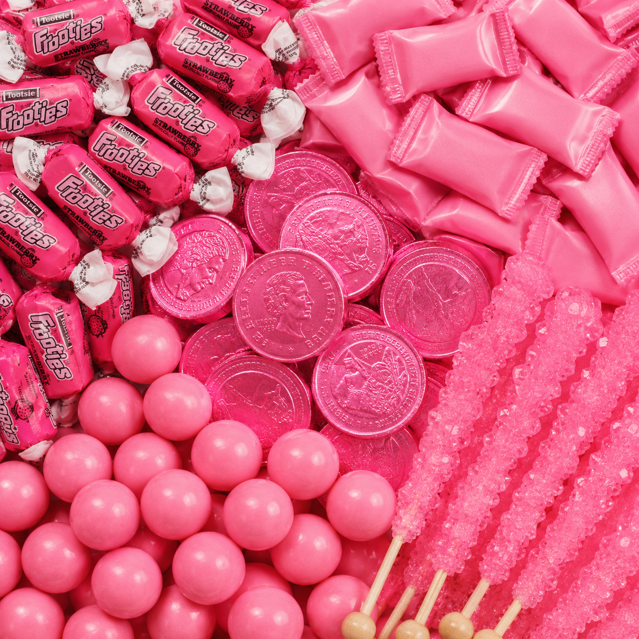 Pink candy assortment featuring strawberry Tootsie Frooties, pink wrapped candies, chocolate coins, gumballs, and rock candy sticks.