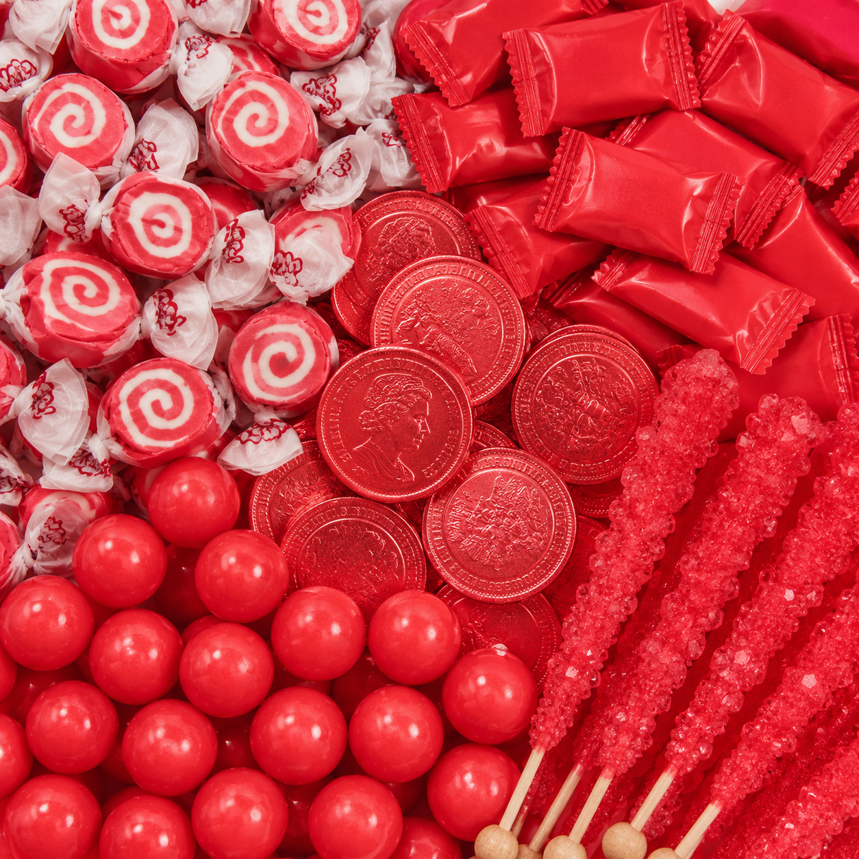 Red candy assortment featuring swirl taffy, red wrapped candies, chocolate coins, gumballs, and rock candy sticks.
