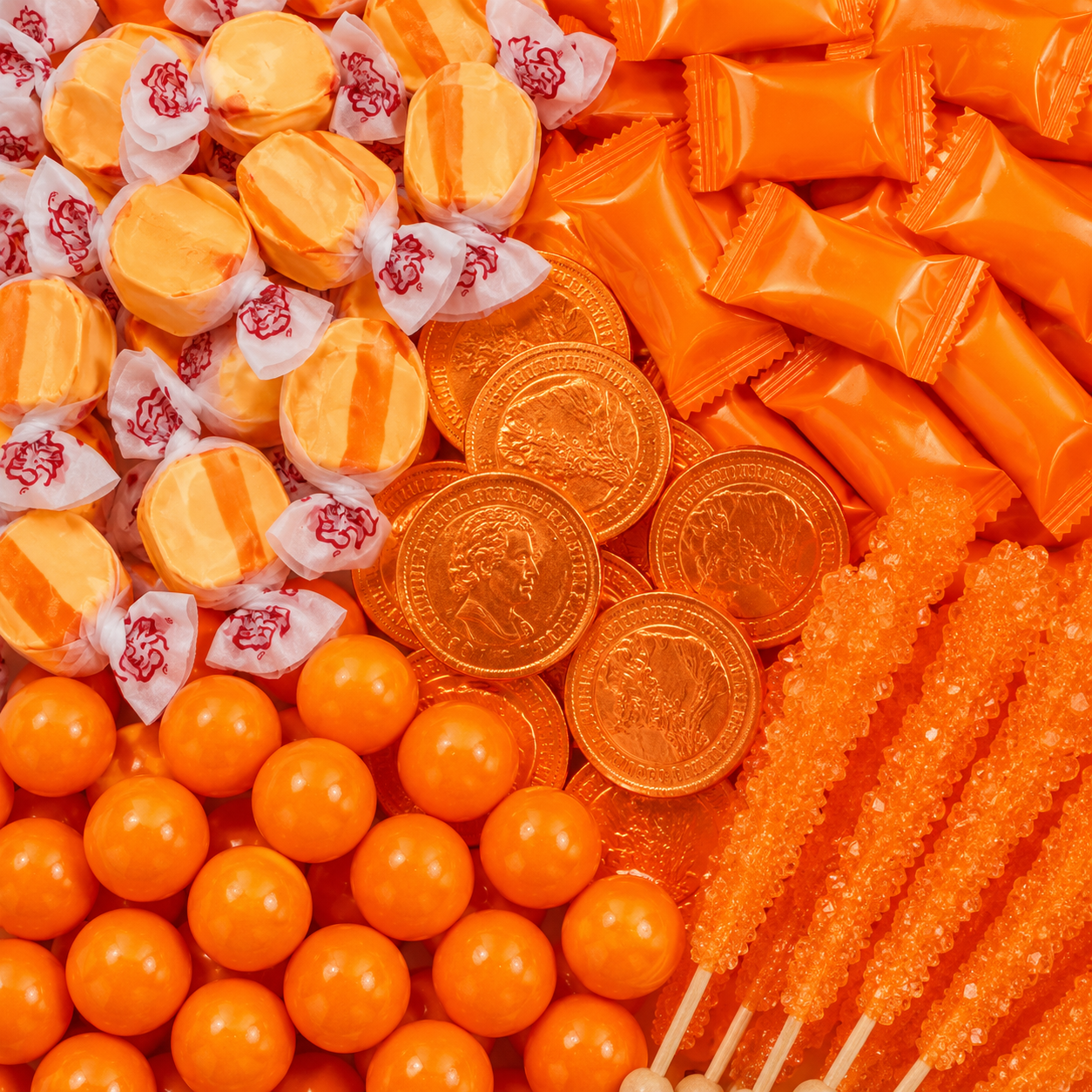 Orange candy assortment featuring striped taffy, orange wrapped candies, chocolate coins, gumballs, and rock candy sticks.