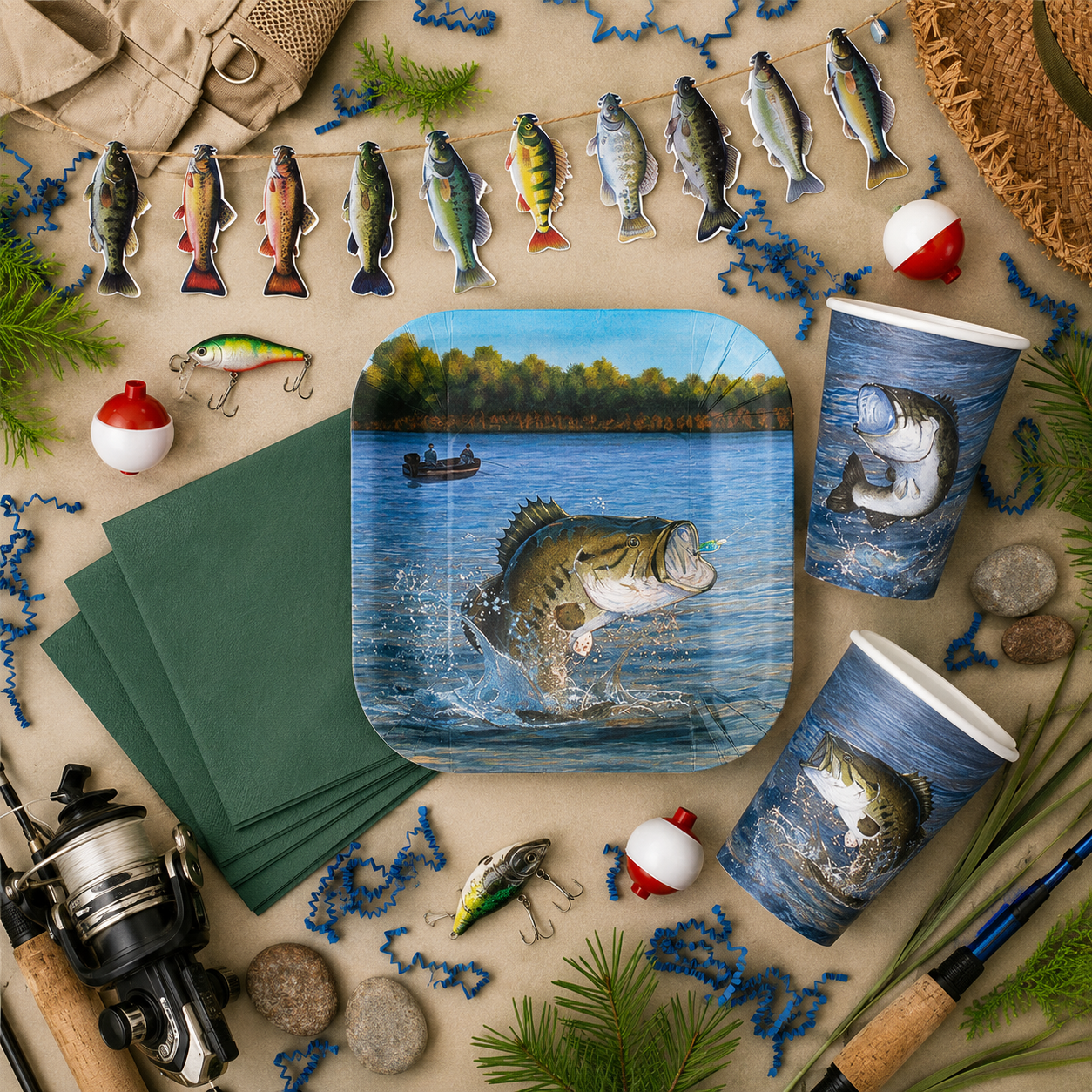 Fishing party setup with bass plates and cups, green napkins, fish garland, bobbers, fishing lures, rods, rocks, greenery, blue paper shred, and outdoor tackle-themed decor.