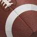 Close-up of football-shaped beverage napkins with brown textured surface and white stripe detail, showing laces at the top.
