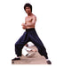 Lifesize cardboard standup of a shirtless man in a martial arts fighting stance wearing dark pants and white socks on a sandy surface against a white background.