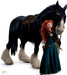 Red-haired girl in a teal dress stands beside a large black horse with white markings on its face and legs, wearing a brown saddle.