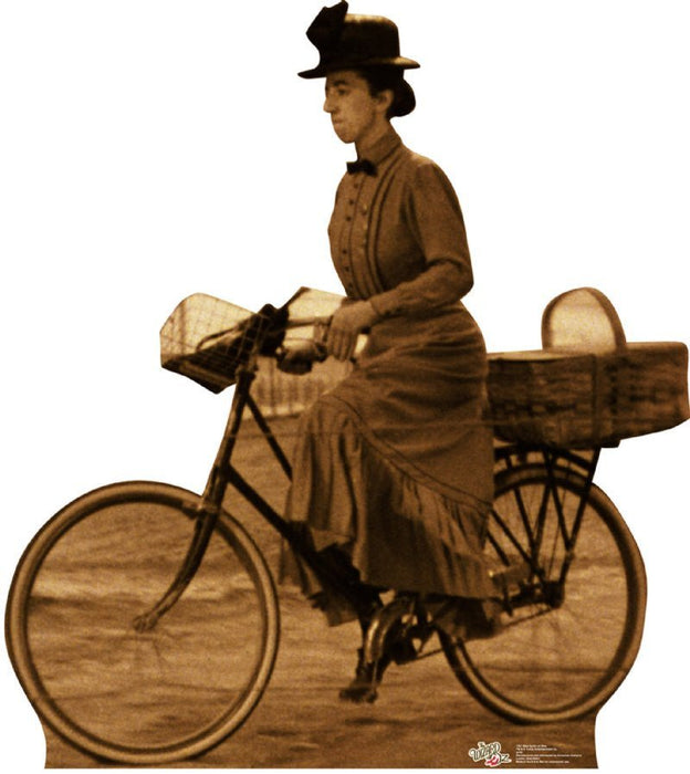 Sepia-toned cardboard standup figure of a woman in a brown dress and black hat sitting on a bicycle with extended arms, resembling a classic film character.