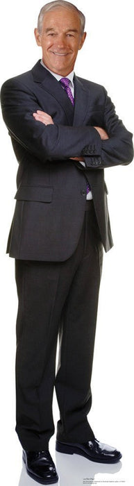 Life-size cardboard cutout of an older man in a dark navy suit with purple patterned tie, standing with crossed arms and smiling at the camera.