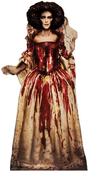 Life-size cardboard standup of a woman in a cream-colored coat and deep red sequined dress with blood drips, featuring dark curled hair and pale complexion.