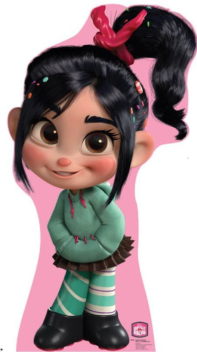 Cardboard standup cutout of an animated girl character with black hair in a ponytail with a pink bow, wearing a green sweater and striped socks against a pink background.