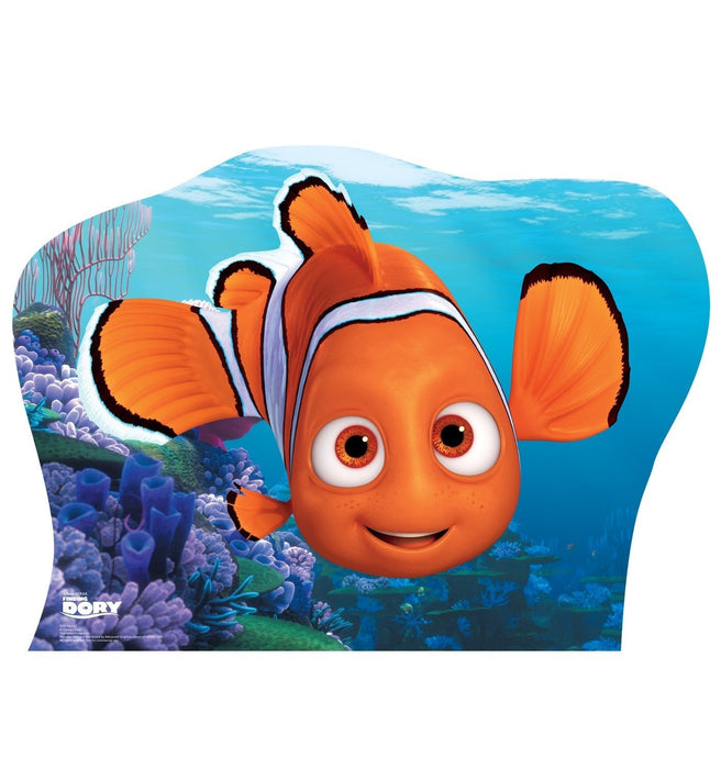 Orange and white clownfish character with large expressive eyes and black-tipped fins, surrounded by colorful coral reef scenery in shades of blue and purple on a die-cut cardboard standup.