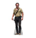Lifesize cardboard standup figure of a man wearing a tan short-sleeved shirt, dark jeans with a studded belt, and brown boots, holding a revolver at his side.