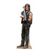 Life-size cardboard standup of a man with shoulder-length brown hair wearing a sleeveless black vest and dark pants, holding a large gray rocket launcher across his body.