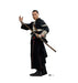Man in black robes with white arm guard holding wooden staff with attached blaster, hand raised, against white background.
