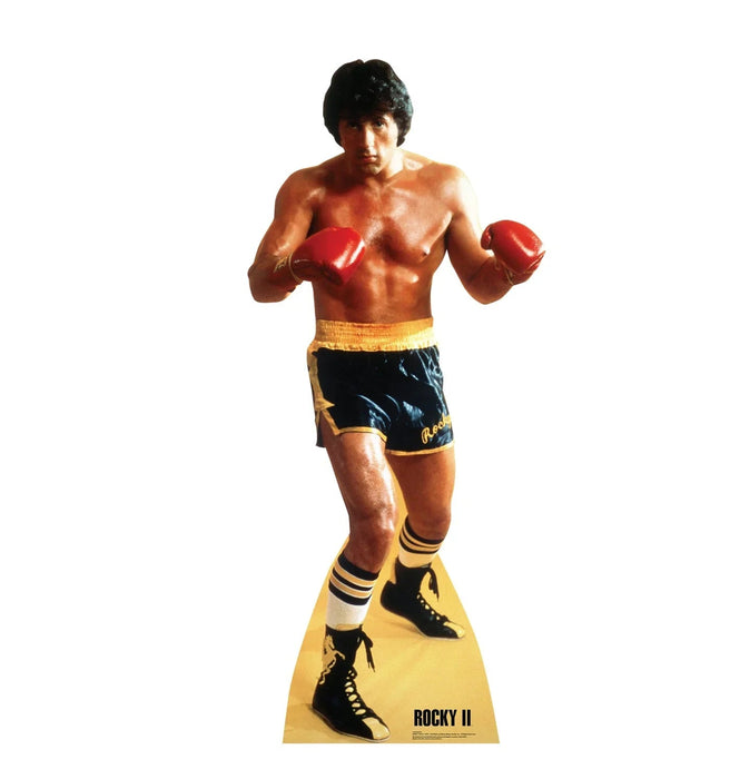Life-size cardboard standup of a boxer in red gloves and black and gold shorts with matching striped socks, labeled Rocky II at the base.