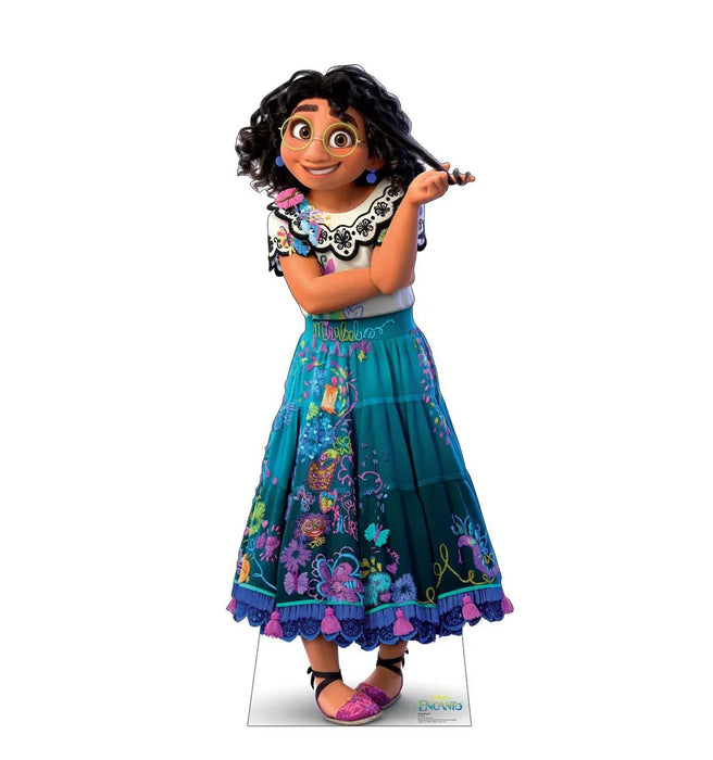 Cardboard standee of an animated girl with black wavy hair, yellow-framed glasses, and a bright smile, wearing a white embroidered collar, colorful floral skirt in teal and purple, and pink sandals.