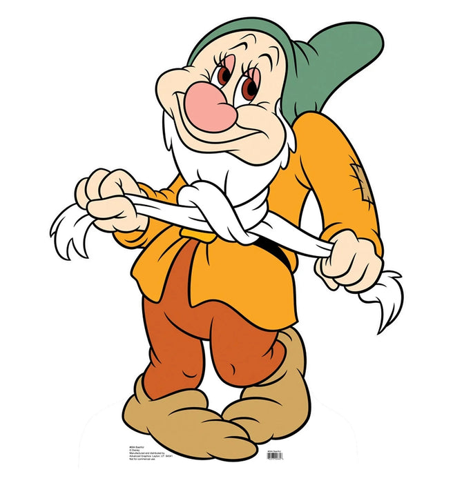 Cheerful cartoon dwarf character with a round pink nose, white beard, green pointed hat, and yellow and orange outfit standing with hands on hips.