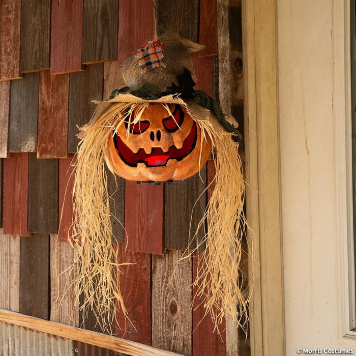 Full-length product photo of the 11 3/4" x 27 1/2" Hanging Pumpkin Head Plastic, shown against a plain white background — designed to hang. It measures about 11 3/4" x 5 3/4" x 27 1/2". A Halloween decoration.