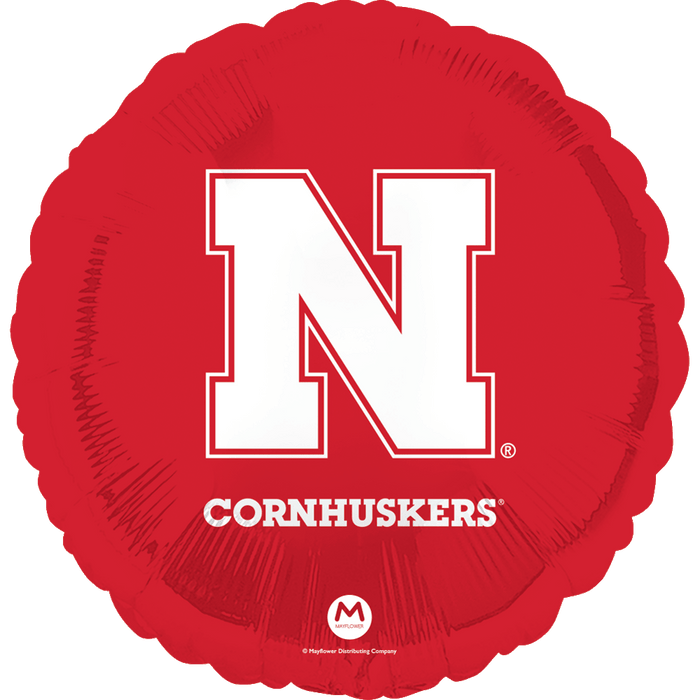 Red round foil balloon featuring a large white N logo with "CORNHUSKERS" text and registered trademark symbols on a bright red background.