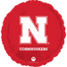 Red round foil balloon featuring a large white N logo with "CORNHUSKERS" text and registered trademark symbols on a bright red background.