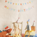 Children's birthday party scene with stuffed animals and 'Happy Birthday' banner.