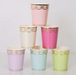 Ladurée Paris Cups in assorted pastel colors with metallic gold garland, bow, and trim details.
