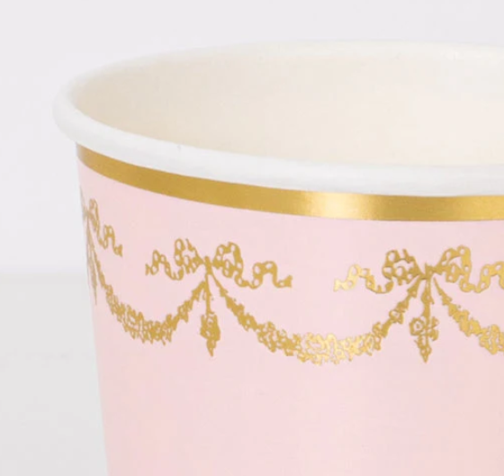 Close up of a Pink Ladurée Paris Cup with metallic gold garland, bow, and trim details.
