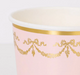Close up of a Pink Ladurée Paris Cup with metallic gold garland, bow, and trim details.
