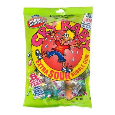 Bright green bag of Cry Baby Extra Sour bubble gum featuring red and yellow cartoon graphics of a crying character, with purple and blue wrapped candies visible through the clear window.