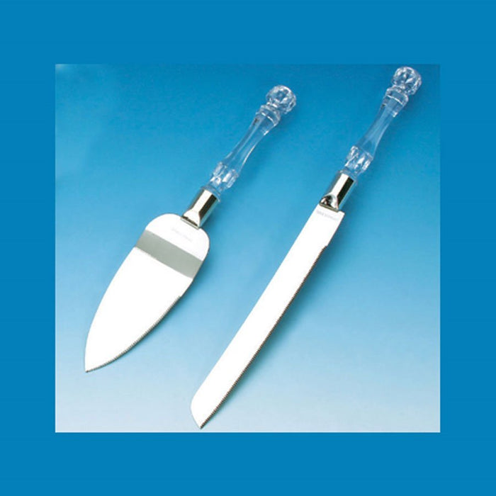 Two white ceramic serving utensils with clear glass handles and silver ferrules, featuring a cake server with rounded blade and a spreader knife, displayed against a blue gradient background.