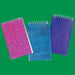 Three glitter spiral notepads in pink, turquoise, and purple with white spiral bindings arranged on a green background.