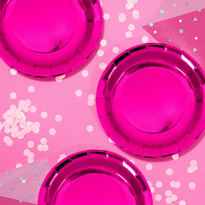 Turning Pink 9-inch paper foil plates with a shiny hot pink metallic finish, styled on a pink party table with confetti, sold in an 8-count pack.
