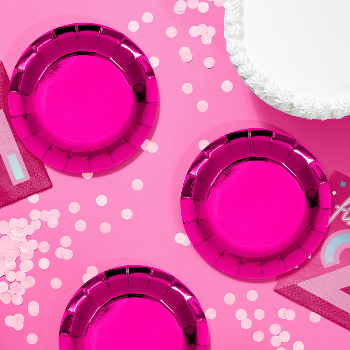 Turning Pink 7-inch paper foil plates in bright hot pink metallic finish, styled on a pink party table with confetti and coordinating party décor, 8-count pack.