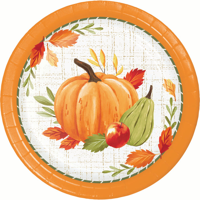 A round paper plate with an autumn harvest design, featuring a large orange pumpkin, a green gourd, a red apple, and orange and red leaves on a white plaid background with a bright orange rim.