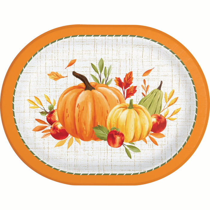 An oval paper plate with a festive autumn design, featuring two pumpkins, apples, a pear, and leaves on a white textured background with an orange rim.