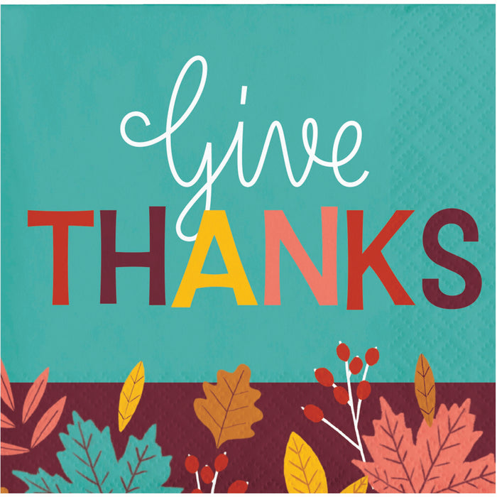 Square napkin with the words 'give THANKS' on a teal background, with autumn leaves and berries along the bottom edge.
