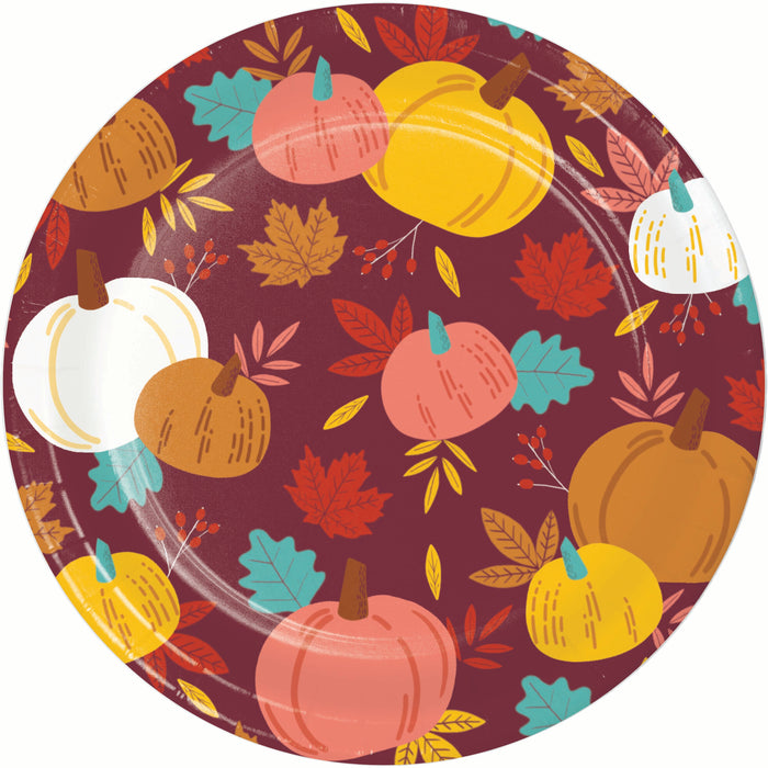 A round paper plate featuring a festive autumn pattern with pumpkins, leaves, and berries on a dark burgundy background.