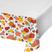 A white tablecloth featuring a colorful autumn pattern of pumpkins, gourds, leaves, and acorns in orange, yellow, red, brown, and teal, shown draped over a table corner against a white background.