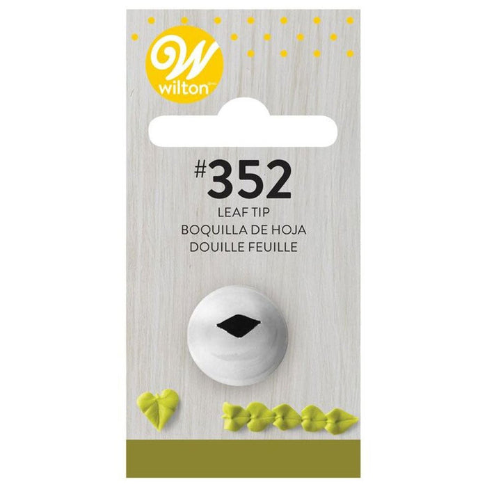 Wilton #352 leaf decorating tip in white metal with a black leaf-shaped opening, displayed on gray wood-grain packaging with yellow accents and bilingual labeling.