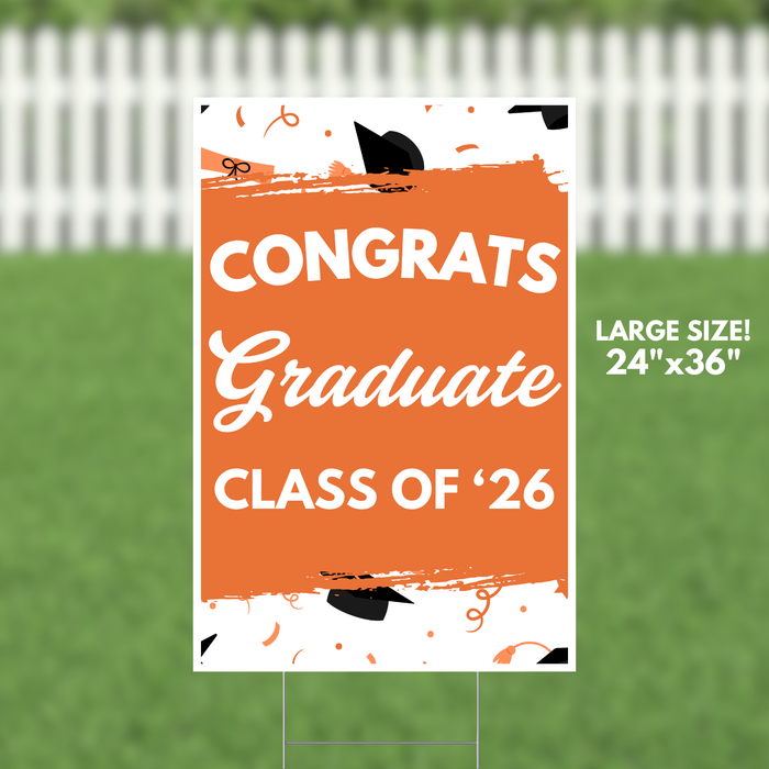 Large orange and white yard sign reading "CONGRATS Graduate CLASS OF '26" with black graduation caps and orange confetti decorations, measuring 24 inches by 36 inches.
