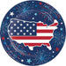 Round patriotic paper plate featuring a map of the United States filled with red and white stripes and white stars, surrounded by a navy blue border decorated with fireworks, stars, and patriotic colors.