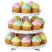 Three-tier white cupcake stand with 15 vanilla cupcakes decorated with pink, green, and yellow frosting rosettes in yellow paper liners.