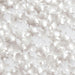 Scattered translucent white and silver star-shaped sprinkles with a sparkling finish on a light background.