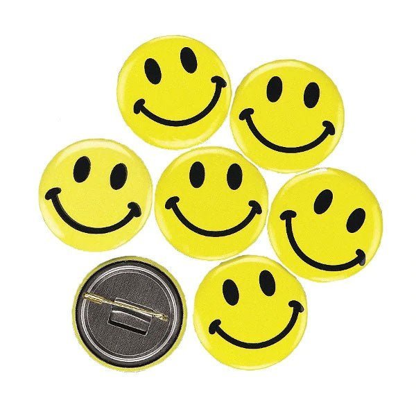 Seven bright yellow smiley face pins with black eyes and smiles arranged in a circle, plus one shown from the back displaying its metal pin fastener.
