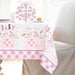 Pink floral elephant baby shower table cover featuring a repeating “Baby” design, pink elephants with gingham ears, floral accents, and matching party items on a bright table setup.