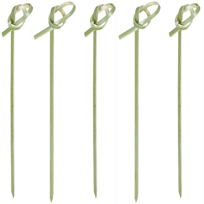 Five green bamboo cocktail picks with decorative loop tops and leaf-shaped frills are arranged in a row against a white background.