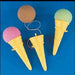Three plush ice cream cone toys with yellow cones and textured pink, brown, and green scoops, two with white string attachments, arranged on a blue background.