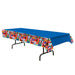 Blue plastic tablecloth with a border strip featuring colorful international flags from countries around the world, displayed on a black folding table.