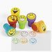 Six colorful smiley face stamp toys in red, yellow, green, blue, and purple with matching ink stamps displayed below showing various happy face designs.