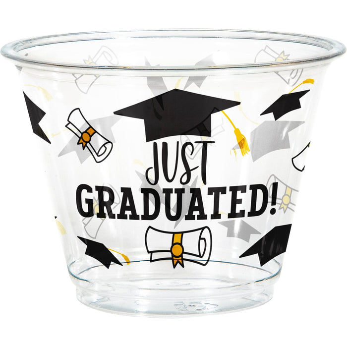 Clear plastic cup printed with "JUST GRADUATED!" text, black graduation caps, diplomas with gold ribbons, and decorative stars in black and gold.