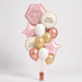 A birthday balloon bouquet featuring metallic rose gold,  gold, white, and pink balloons, including star and round foil balloons with 'Happy Birthday' text, arranged on a light gray background.