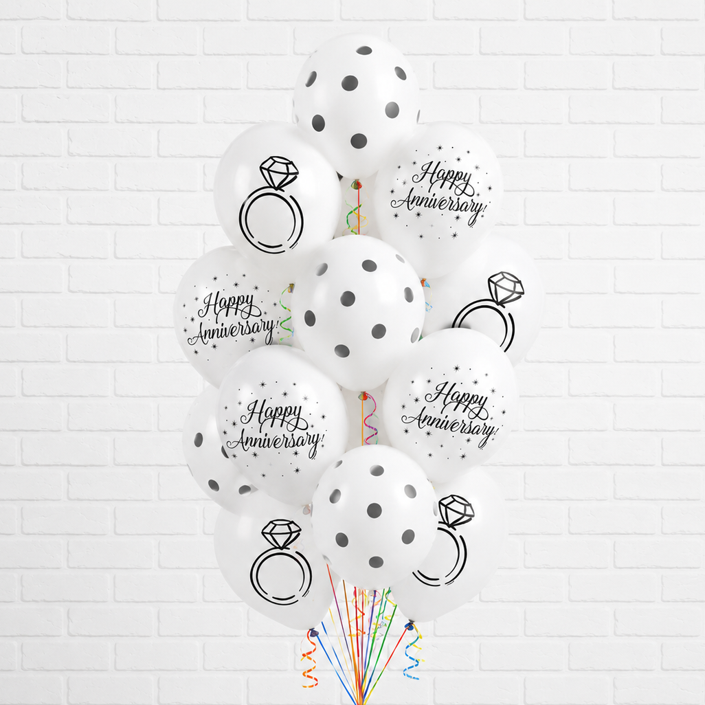 Decorative balloons with 'Happy Anniversary' and ring designs on a white brick wall background.