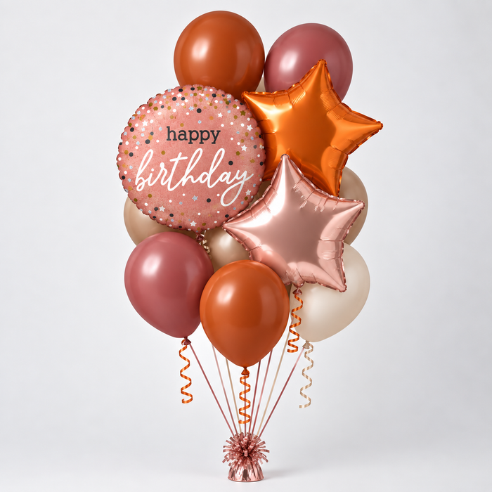 A balloon bouquet featuring a pink foil balloon with 'happy birthday' text, metallic orange and rose gold star balloons, matte orange and dusty rose round balloons, and cream balloons, tied together with ribbons on a light gray background.